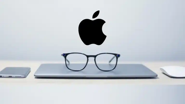apple laptop üstünde gözlük ve onun üstünde apple logosu var