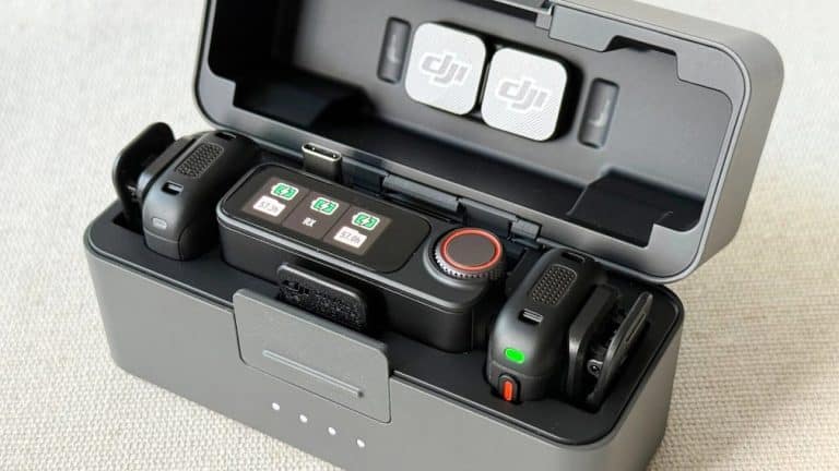 DJI Mic 3 şarj kutusu açık halde, içinde iki verici ve bir alıcı düzenli şekilde yerleştirilmiş, ekranlarında şarj seviyeleri görünüyor ve kutu kapağında manyetik klipsler saklanıyor.