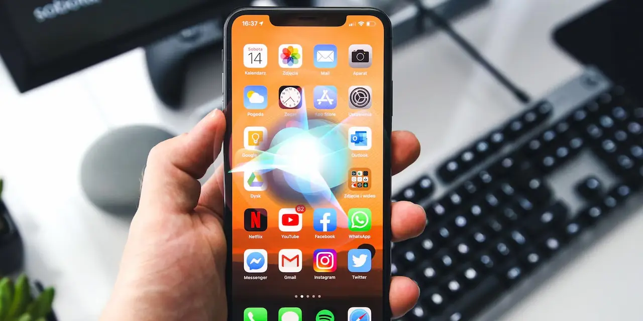 iPhone’da Hey Siri çalışmıyor sorununu çözmek için ayarlar ekranı açık şekilde elde tutulan iPhone görseli – Siri simgesi parlayan ekran görüntüsü