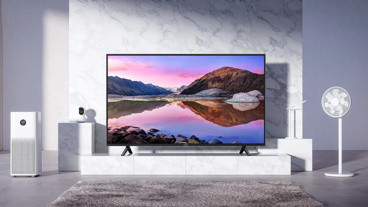 Xiaomi akıllı TV, beyaz mermer desenli duvara yaslanmış ünitede, yanında hava temizleyici ve akıllı vantilatör.
