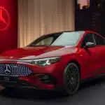 Tanıtım alanında sergilenen kırmızı Mercedes CLA 350 4MATIC, ön ızgara ve sportif coupe sedan tasarımıyla görünüyor.