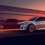 Peugeot E-208 GTi, kırmızı klasik Peugeot 205 GTi ile birlikte gün batımı atmosferinde yolda ilerliyor.