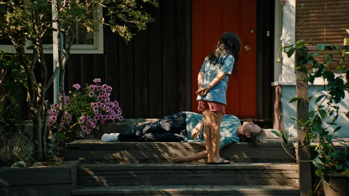 Blue Heron filminden, bir çocuğun evin verandasında yerde yatan bir yetişkine baktığı sahne